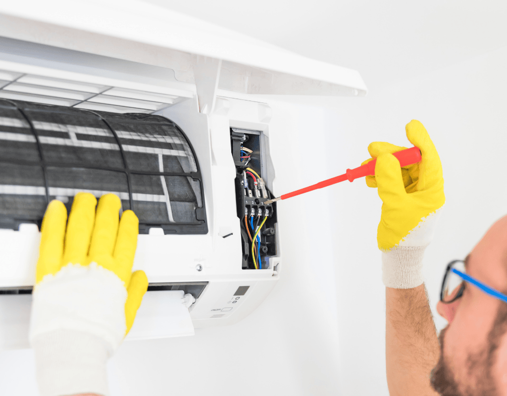 Air conditioning technician repairing electrical components inside a cooling unit in Greater Seattle